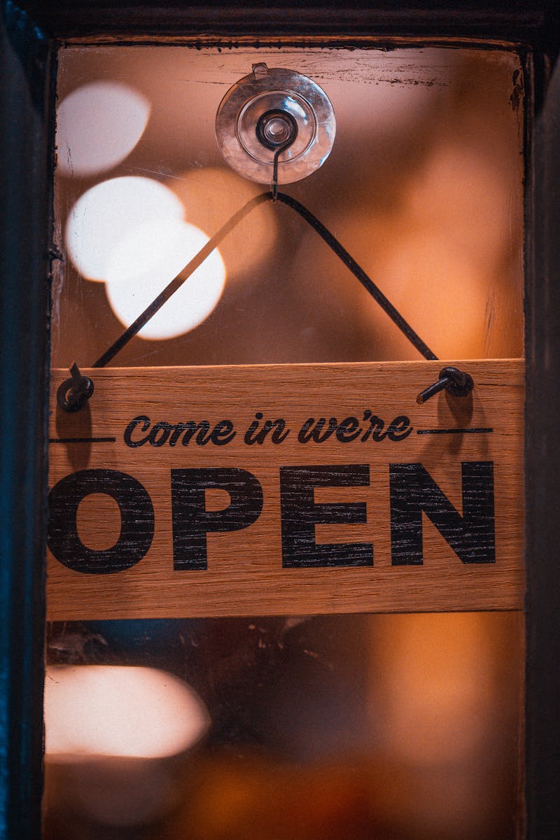 Close-up of a vintage 'Come in we're open' sign with a soft bokeh in a London cafe.